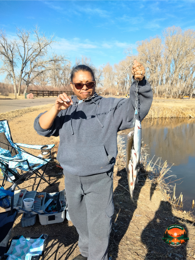 Woman holding a string of freshly caught fish by a pond in Weld County, Colorado on a sunny day